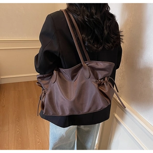 Détail du sac de voyage en nylon marron avec cordon de serrage porté par une femme