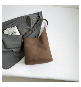 Detail of a brown suede bucket bag with adjustable strap and fine matte texture