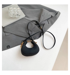 Detalle de bolso bandolera de media luna negro con hebilla dorada en fondo blanco