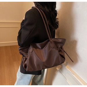 Détail d'un grand sac de voyage marron montrant la texture en nylon et le cordon latéral
