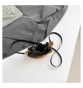 Detalle de bolso medialuna negro mate con cadena dorada gruesa y cierre cremallera