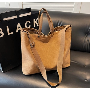 Detailed view of caramel brown canvas tote bag with adjustable strap on leather sofa