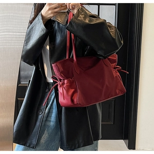 Vue détaillée du grand sac de voyage rouge en nylon avec poches latérales à cordon serrage