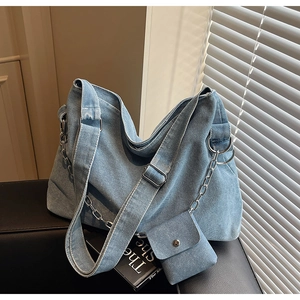 Detail view of washed blue denim tote with silver chain and detachable mini pouch