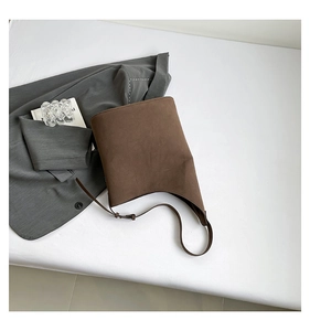 Detail of dark brown matte leather shoulder bag with adjustable strap on white surface