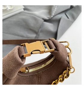 Detalle de bolso medialuna de ante marrón oscuro con hebilla de metal y cadena vintage