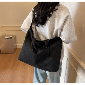 Large capacity black canvas tote bag shown worn on shoulder for daily commute use