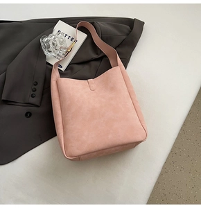 Close-up of minimalist pink matte suede shoulder bag with wide strap on white background