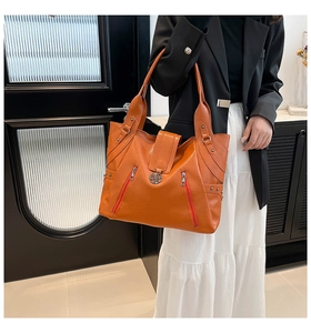 Detailed view of an orange lychee-grain tote bag with side zippers and metal rivets