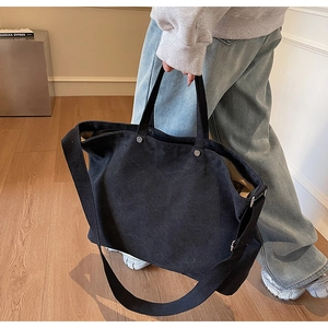 Detailed view of black canvas tote bag with metal rivets and adjustable shoulder strap