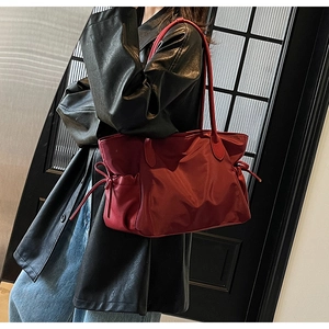Vue détaillée d'un grand sac fourre-tout bordeaux en nylon avec cordons décoratifs