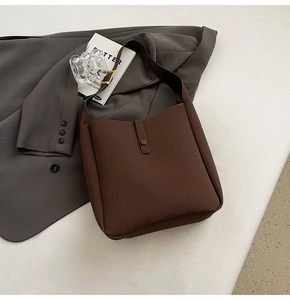 Detail view of dark brown faux leather bag with vertical decorative buckle and soft matte texture