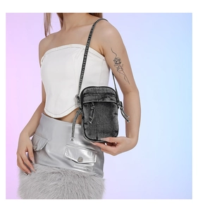 Detail of washed denim crossbody phone bag with knot drawstrings and metal zipper