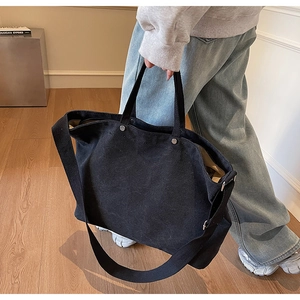 Detail of black canvas tote bag with metal studs and wide crossbody shoulder strap