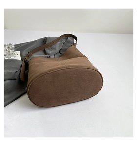 Detail view of the brown suede bucket bag with adjustable strap and side stitching