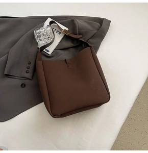 Detail shot of the brown leather hobo bag showing adjustable strap and gold buckle on a blazer