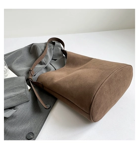 Detail of dark brown faux suede bucket bag with adjustable leather strap and side stitching
