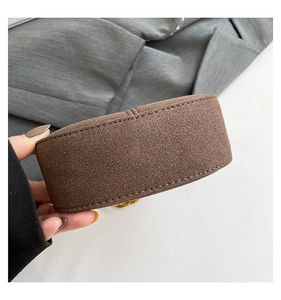 Primer plano de bolso bandolera de ante café con costuras finas y detalles de cadena