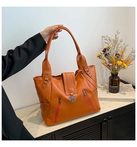 Detail view of large orange PU leather tote bag with decorative zippers and metal buckles