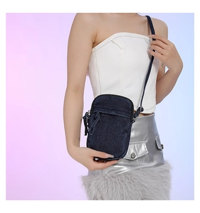 Mini washed denim crossbody phone bag with zipper closure shown on a female model