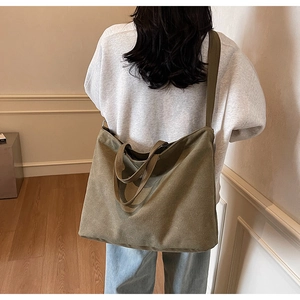 Detail of a large olive canvas tote bag worn by a model in a minimalist modern interior