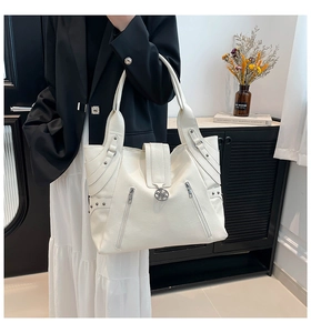 Detail of white PU tote bag showing lychee texture, silver zippers, and petal metal buckle