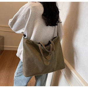 Rear view detail of a large olive green canvas tote bag worn by a model for daily commute