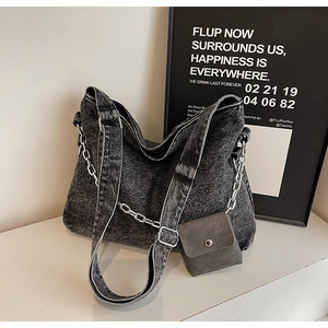 Detail of black washed denim tote bag featuring silver chain and small square pouch