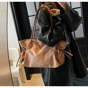 Détail d'un grand sac de voyage en nylon marron avec cordons latéraux et anses en cuir
