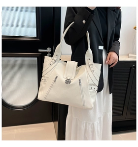 Detail of ivory PU tote bag showing pebbled leather texture and metal rivet accents