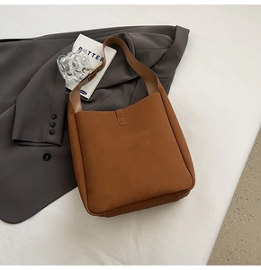 Detailed view of brown minimalist shoulder bag with matte finish on white surface
