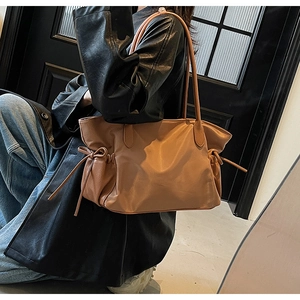 Détail du sac cabas marron caramel avec texture cuir et nœud décoratif sur le côté