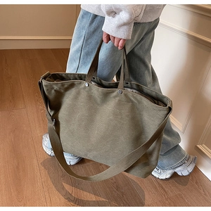 Detail view of olive green canvas tote bag featuring reinforced handles and metal buckle