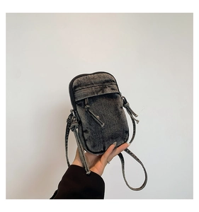 Detail shot of distressed dark grey denim mini crossbody bag with drawstring design