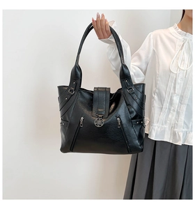 Detail view of black lychee grain tote bag with decorative side zippers and metal pendants