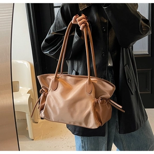 Détail du sac de voyage marron clair avec nœuds de serrage latéraux et texture grainée