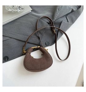 Detalle de un mini bolso de media luna en ante marrón con elegante hebilla dorada fina