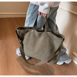 Detail of army green canvas tote showing thick fabric texture and silver rivet reinforcement