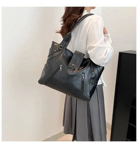 Detail of black pebbled PU leather tote featuring silver flower buckle and zipper decor