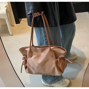 Détail du sac de voyage taupe avec cordon de serrage latéral et poignées en cuir