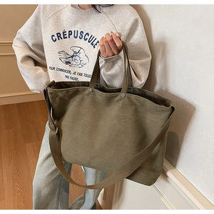 Detail view of large olive green canvas tote bag with sturdy handles and shoulder strap