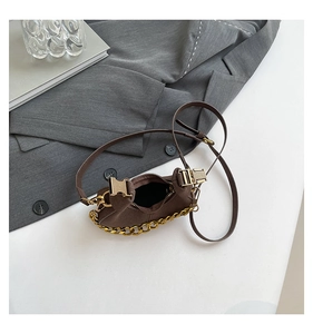 Detalle del mini bolso medialuna en ante marrón con cadena dorada y espacio interior