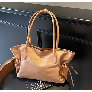 Vue latérale d'un sac cabas en cuir marron avec cordon de serrage sur fond de bois sombre