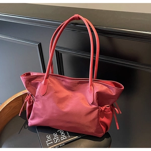 Détail du sac de voyage en nylon rouge foncé avec côtés à cordon et texture en cuir