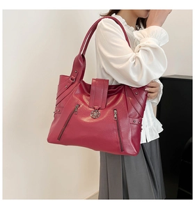 Detail view of wine red PU leather tote bag with decorative zippers and lychee texture