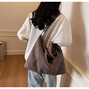 Deep brown canvas tote bag detail showing wide straps and slouchy casual commuter style
