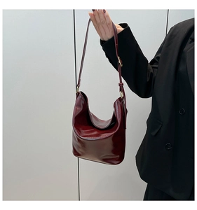Detail of dark red glossy patent leather tote bag with metallic buckle and soft texture