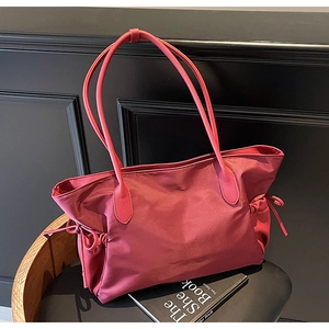 Détail du sac cabas en nylon bordeaux imperméable avec poignées en cuir et cordons latéraux