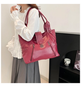 Close-up of wine red faux leather tote bag with decorative zippers and metal rivets