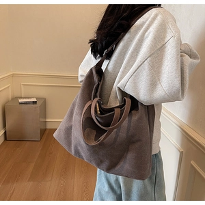 Detail view of large brown canvas tote bag worn by model in minimalist studio